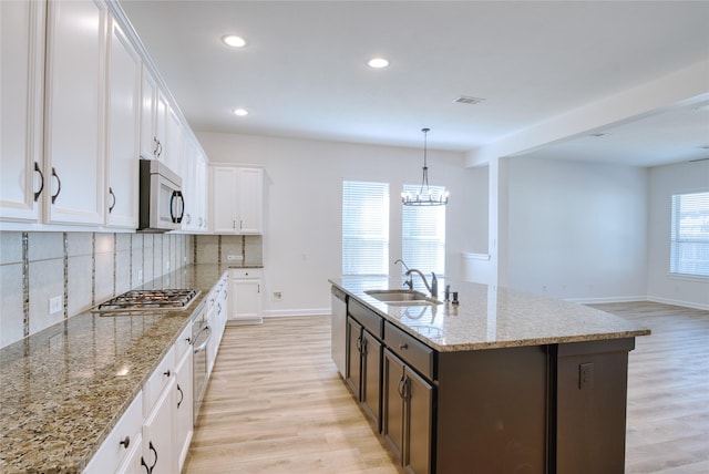 kitchen featuring decorative backsplash, sink, white cabinets, and appliances with stainless steel finishes