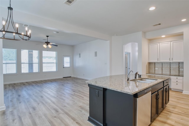 kitchen featuring stainless steel dishwasher, white cabinets, sink, and an island with sink