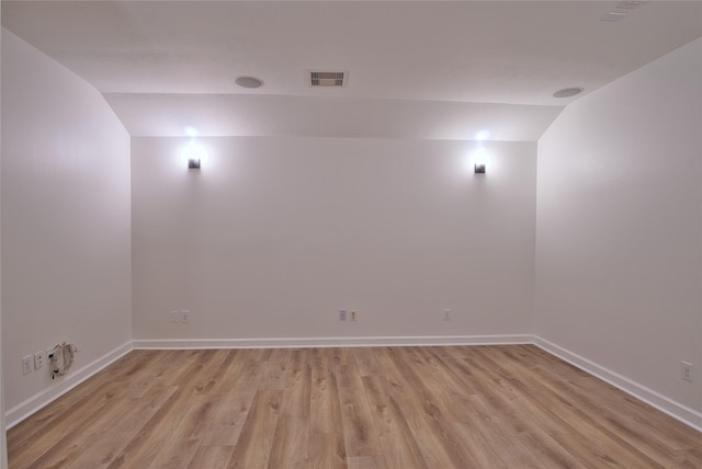 spare room with light hardwood / wood-style flooring and vaulted ceiling