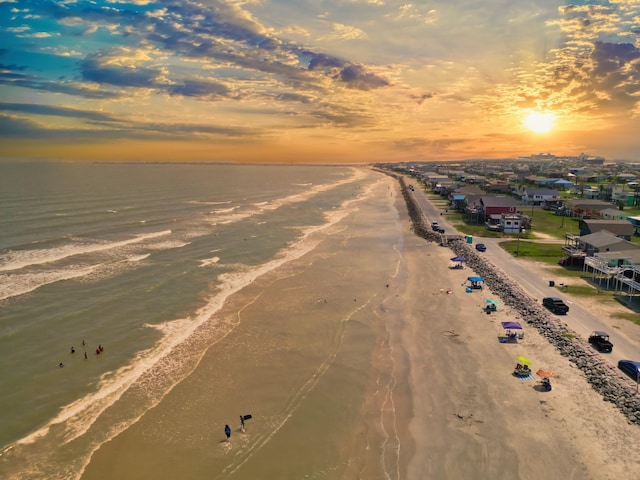 aerial view at dusk with a water view and a beach view