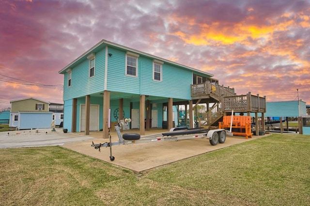 back house at dusk with a yard, a deck, and a carport