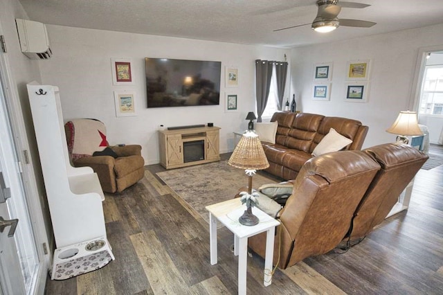 living room featuring ceiling fan, dark hardwood / wood-style flooring, an AC wall unit, and a textured ceiling