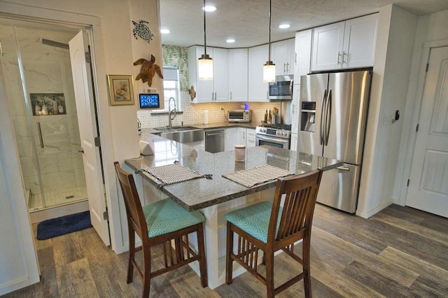 kitchen with pendant lighting, white cabinetry, sink, and stainless steel appliances