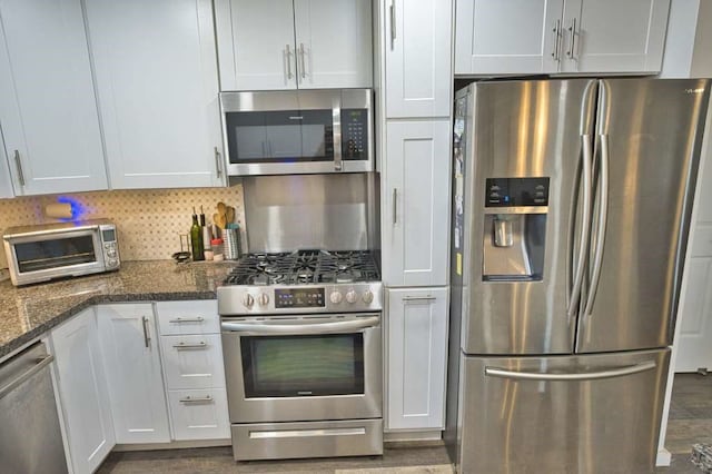 kitchen featuring decorative backsplash, dark hardwood / wood-style flooring, stainless steel appliances, dark stone countertops, and white cabinets