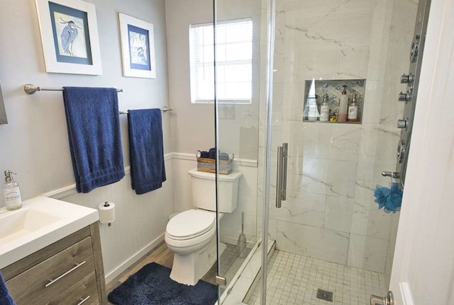 bathroom with baseboard heating, hardwood / wood-style floors, toilet, vanity, and a shower with shower door