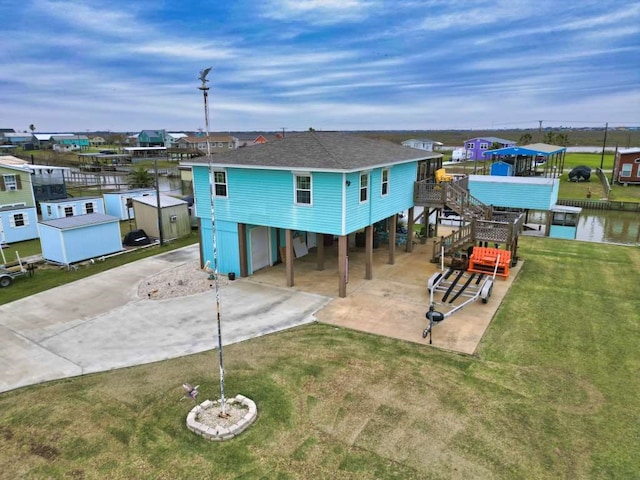 rear view of house featuring a carport, a water view, and a yard