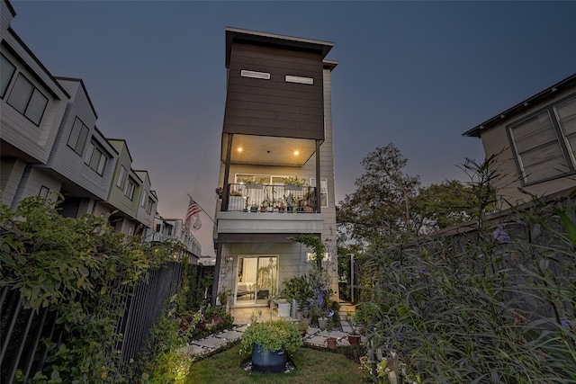 back house at dusk featuring a balcony