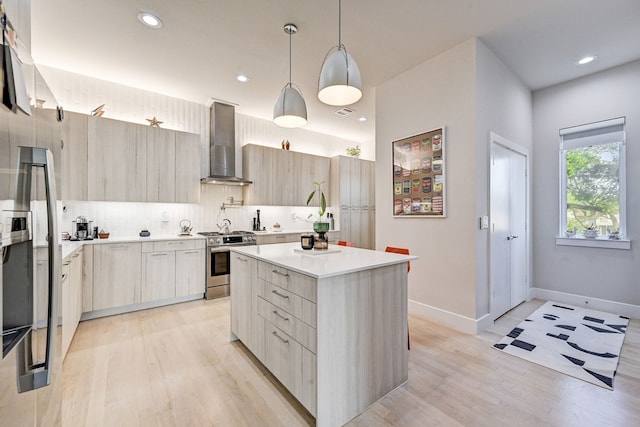 kitchen featuring a center island, backsplash, wall chimney range hood, appliances with stainless steel finishes, and decorative light fixtures