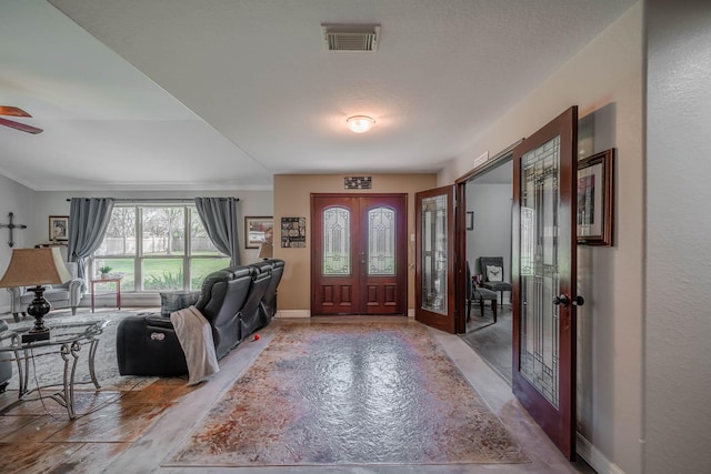 foyer entrance with ceiling fan, a textured ceiling, and french doors