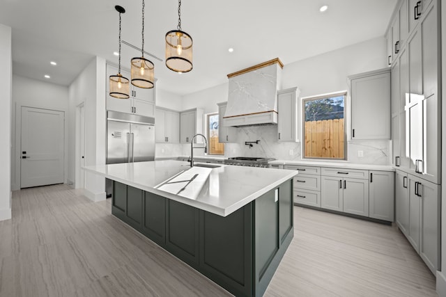 kitchen with a center island with sink, gray cabinetry, tasteful backsplash, and sink