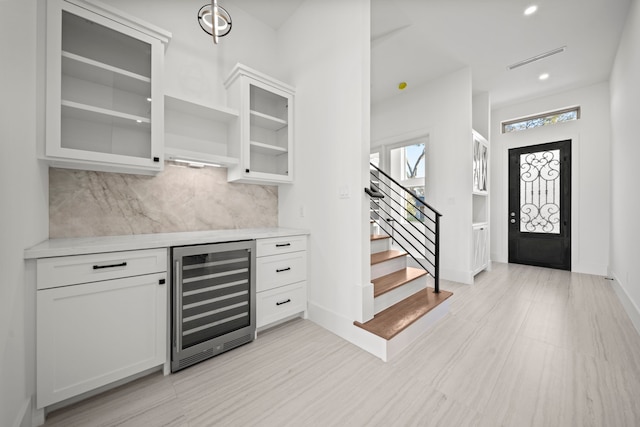 bar featuring white cabinetry, decorative backsplash, and wine cooler