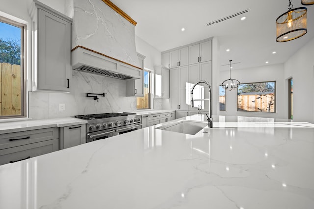 kitchen featuring sink, decorative backsplash, stainless steel stove, and light stone countertops