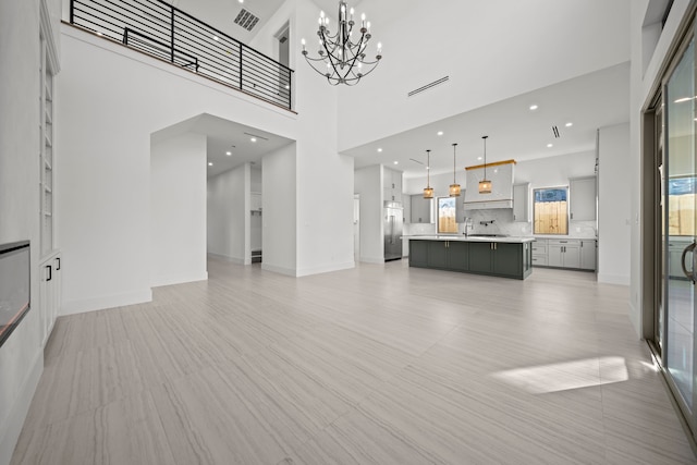 living room with sink, a high ceiling, and a notable chandelier