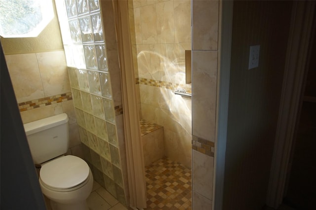 bathroom featuring tile patterned floors, toilet, a shower, and tile walls