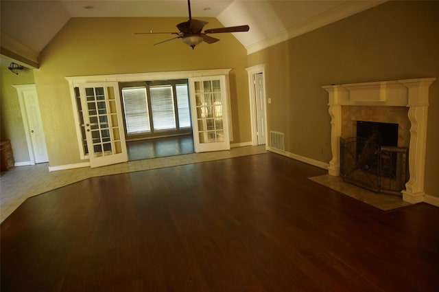 unfurnished living room featuring ceiling fan, french doors, lofted ceiling, a fireplace, and hardwood / wood-style flooring