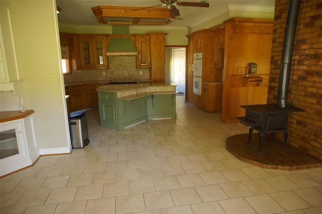 kitchen featuring ceiling fan, a center island, a breakfast bar area, custom range hood, and ornamental molding