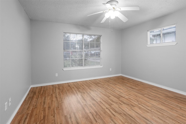 empty room with a textured ceiling, light wood-type flooring, and plenty of natural light