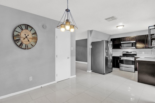 kitchen featuring dark brown cabinets, stainless steel appliances, sink, decorative light fixtures, and light tile patterned flooring