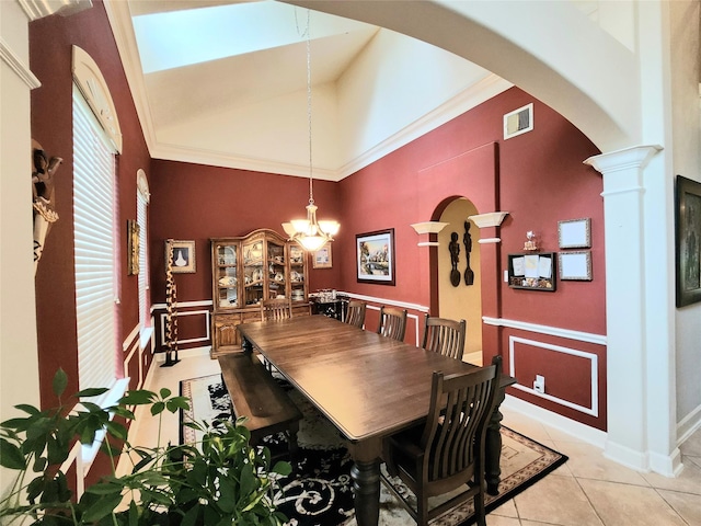 dining area with light tile patterned flooring, lofted ceiling, ornate columns, a chandelier, and ornamental molding