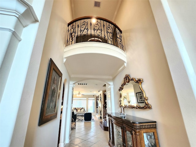 hallway with light tile patterned floors, a high ceiling, and ornamental molding