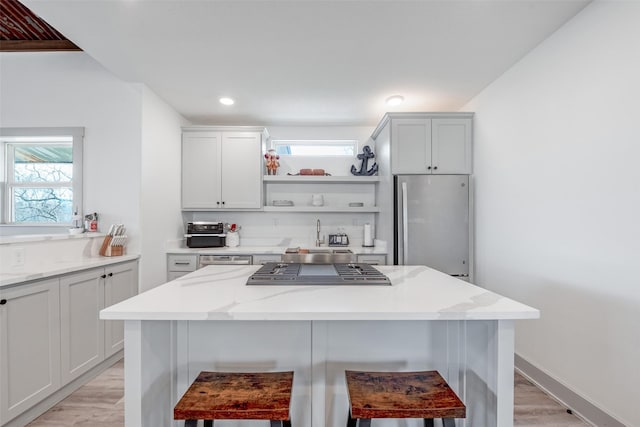 kitchen featuring light stone countertops, a kitchen bar, stainless steel appliances, and white cabinets