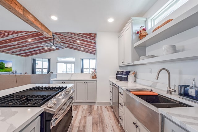 kitchen featuring vaulted ceiling with beams, light stone counters, light hardwood / wood-style flooring, white cabinets, and appliances with stainless steel finishes