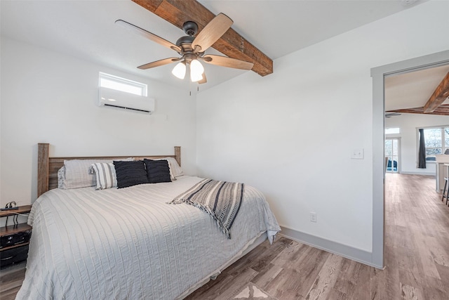 bedroom featuring beamed ceiling, ceiling fan, light hardwood / wood-style floors, and a wall mounted air conditioner