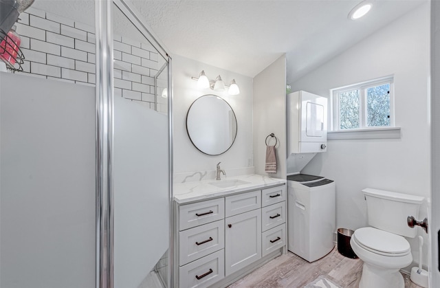 bathroom featuring stacked washing maching and dryer, walk in shower, vanity, hardwood / wood-style floors, and lofted ceiling