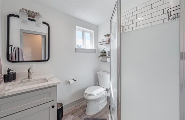 bathroom with vanity, hardwood / wood-style flooring, toilet, a textured ceiling, and a shower with shower door