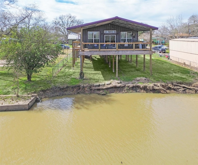 back of house with a lawn and a deck with water view