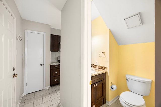 bathroom featuring lofted ceiling, toilet, vanity, tile patterned flooring, and backsplash