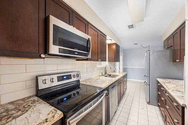 kitchen featuring sink, appliances with stainless steel finishes, backsplash, light stone counters, and light tile patterned flooring