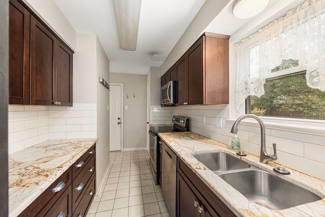 kitchen featuring sink, light tile patterned floors, appliances with stainless steel finishes, light stone counters, and tasteful backsplash