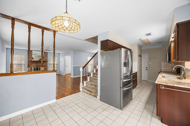 kitchen featuring light tile patterned flooring, sink, appliances with stainless steel finishes, light stone countertops, and decorative backsplash