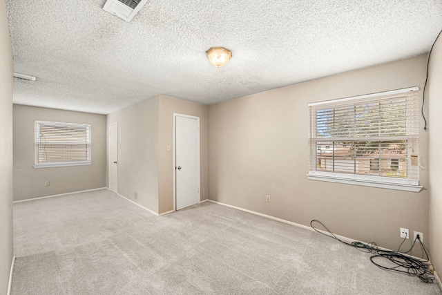 empty room with light carpet and a textured ceiling