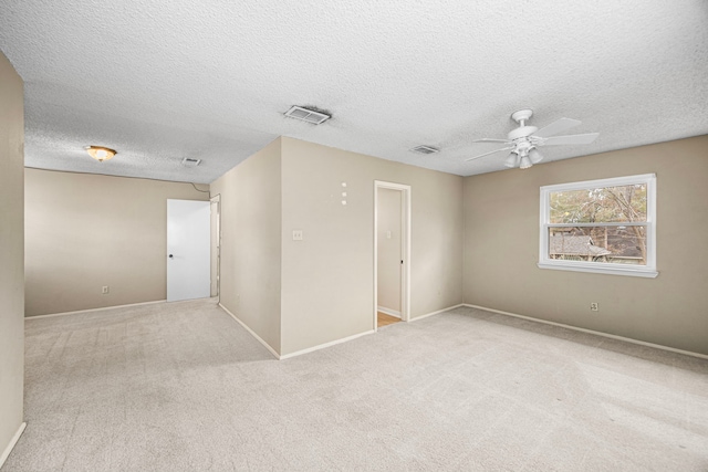 carpeted spare room featuring ceiling fan and a textured ceiling