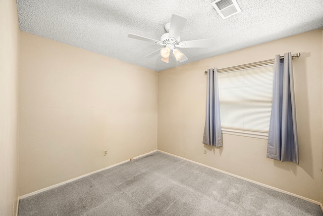 empty room with ceiling fan, light colored carpet, and a textured ceiling