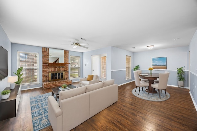 living room with ceiling fan, a brick fireplace, and dark hardwood / wood-style flooring