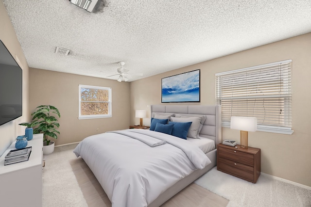 bedroom featuring a textured ceiling, light colored carpet, and ceiling fan