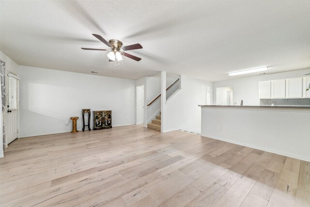 unfurnished living room featuring a textured ceiling, light hardwood / wood-style floors, and ceiling fan