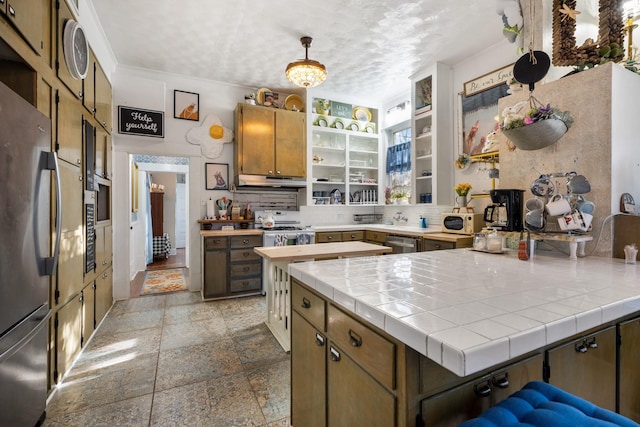 kitchen featuring tile countertops, decorative backsplash, ornamental molding, decorative light fixtures, and stainless steel appliances