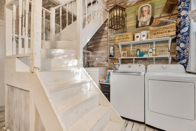 washroom with washer and dryer and wood walls