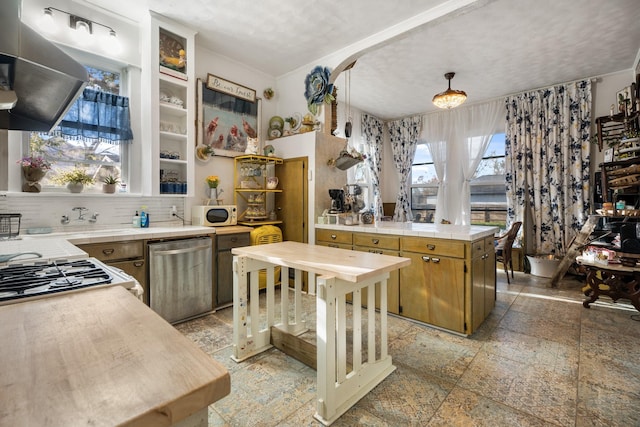 kitchen featuring pendant lighting, backsplash, stainless steel dishwasher, a textured ceiling, and range hood