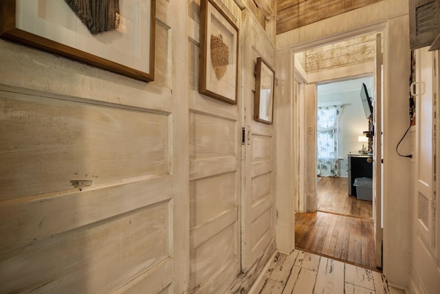 corridor featuring wooden walls and light hardwood / wood-style floors