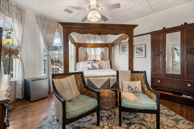 bedroom with hardwood / wood-style floors, ceiling fan, and refrigerator