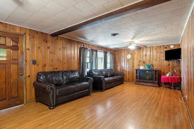 living room with ceiling fan, beamed ceiling, wood-type flooring, and wood walls