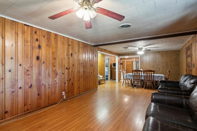 living room with wooden walls, light hardwood / wood-style floors, and crown molding