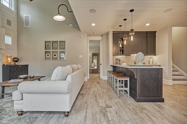 living room featuring a high ceiling, light wood-type flooring, wooden ceiling, and a healthy amount of sunlight