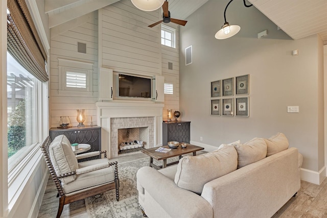 living room featuring a fireplace, high vaulted ceiling, plenty of natural light, and light wood-type flooring