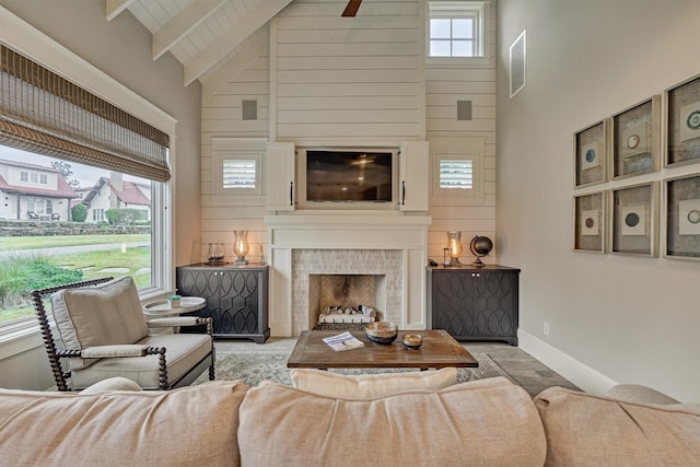 living room featuring beam ceiling, a fireplace, high vaulted ceiling, and plenty of natural light